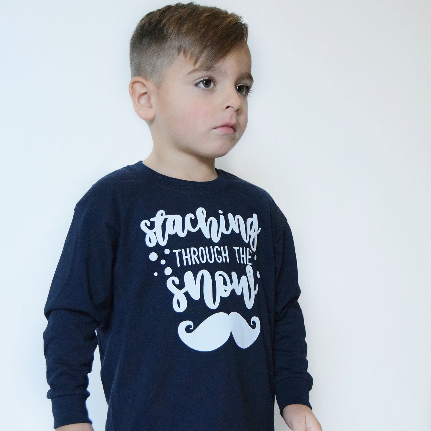 Serious young boy wearing navy shirt with long sleeves with 'Staching through the snow' print by KMLeon.
