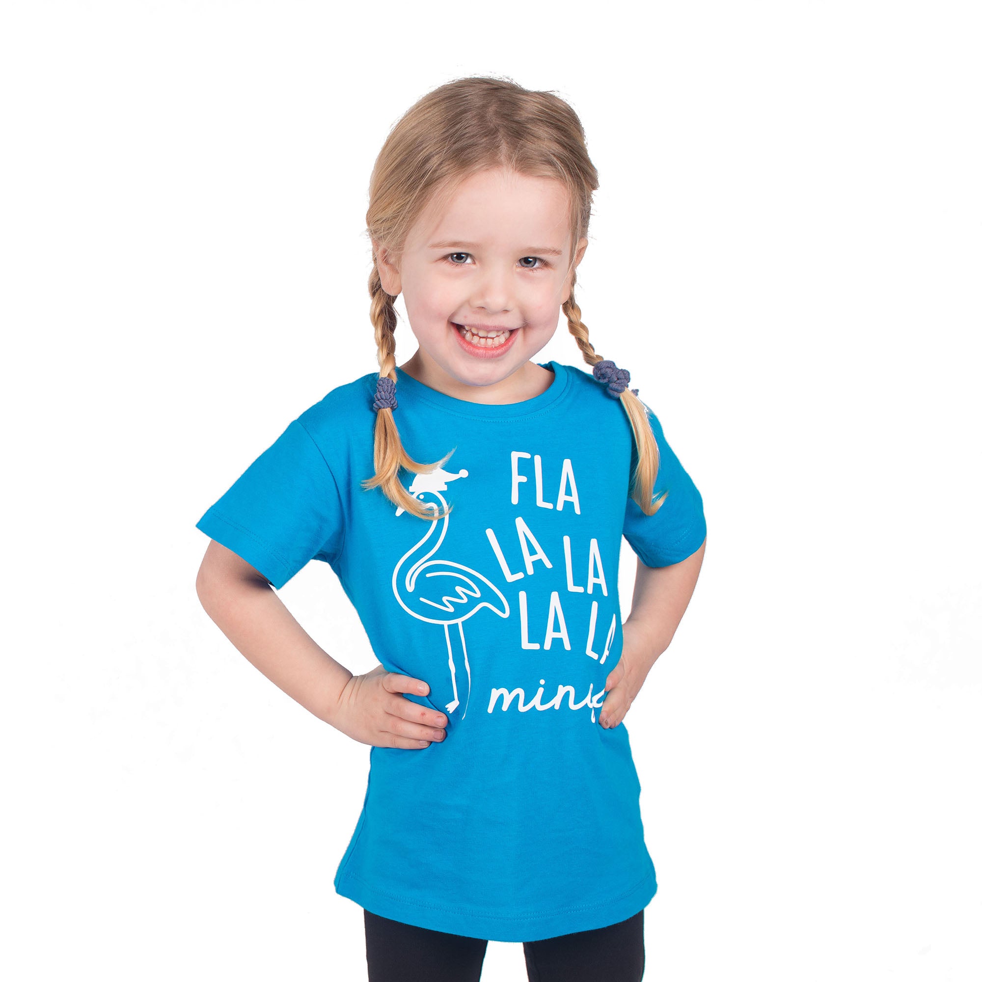Smiling blonde girl with pigtails wearing aqua shirt with 'Fla la la la la mingo' print by KMLeon with hands to her sides.