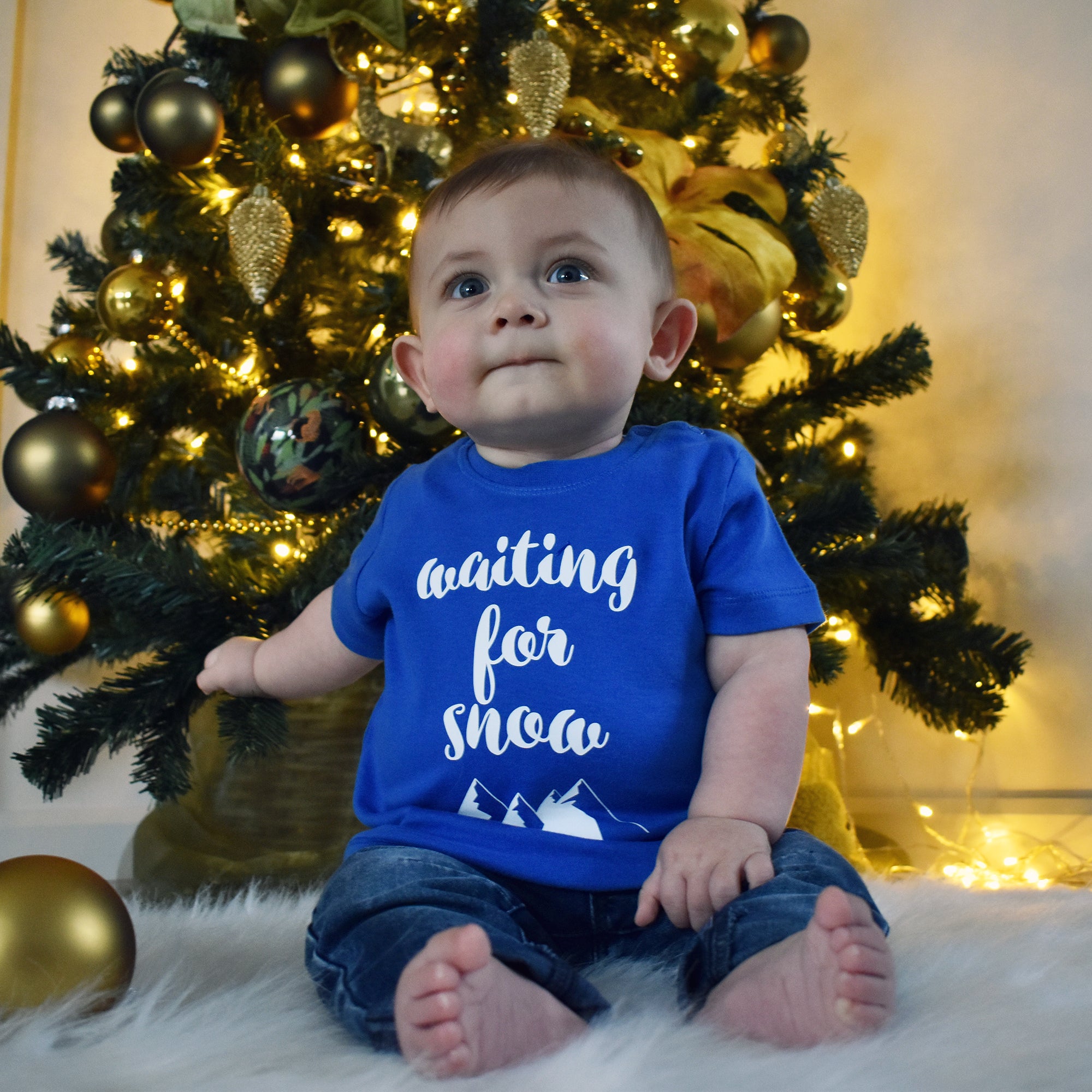 Little boy in front of christmas tree, wearing blue shirt with 'Waiting for snow' print by KMLeon.