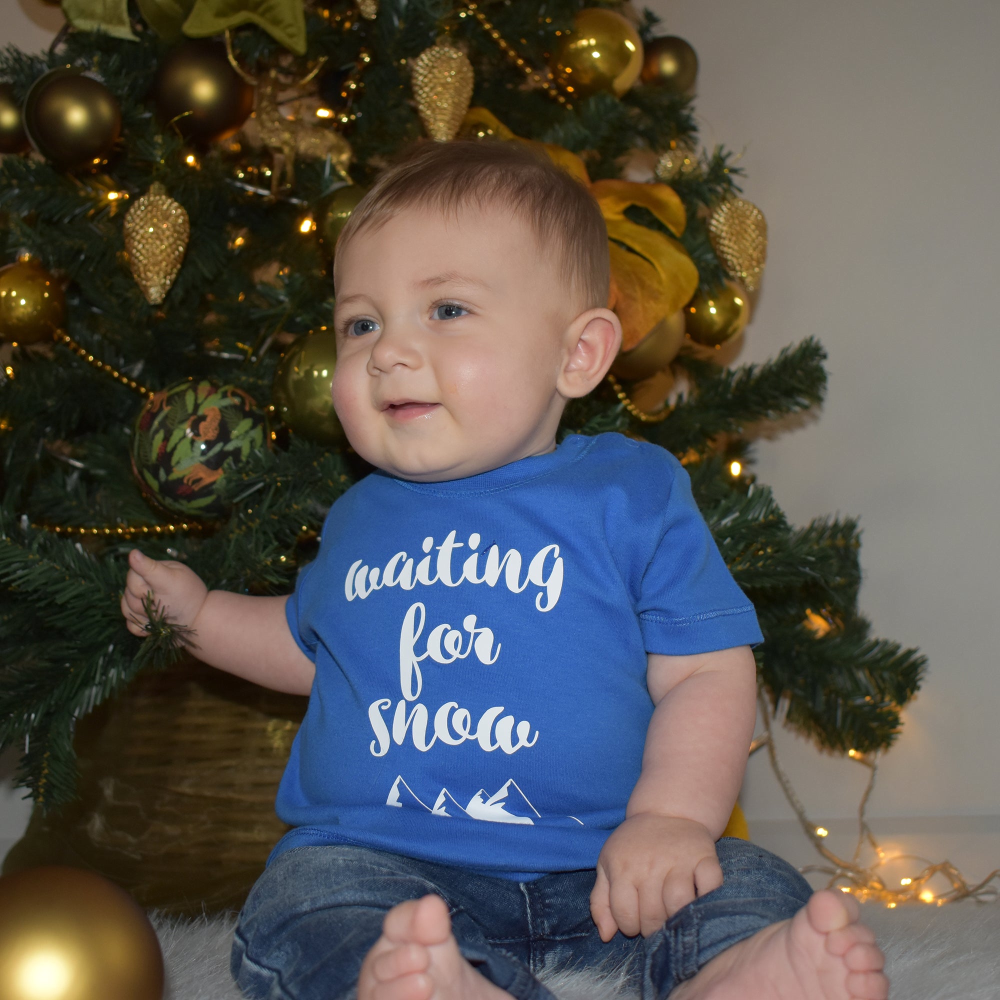 Little boy in front of christmas tree, wearing blue shirt with 'Waiting for snow' print by KMLeon.