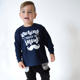 Laughing young boy wearing navy shirt with long sleeves with 'Staching through the snow' print by KMLeon.