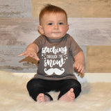Smiling toddler boy wearing mocha shirt, with 'Staching through the snow' print by KMLeon.