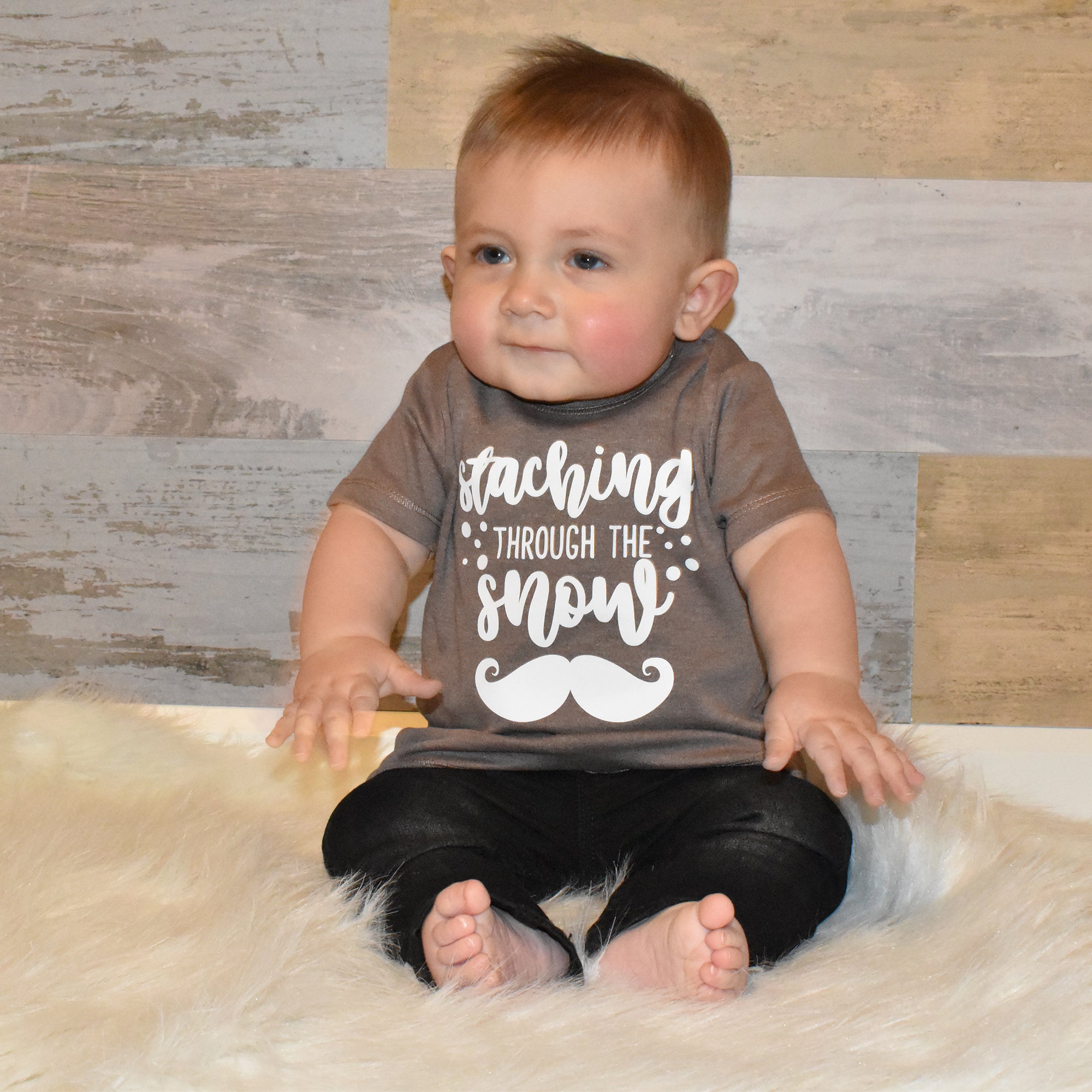 Toddler boy wearing mocha shirt, with 'Staching through the snow' print by KMLeon.