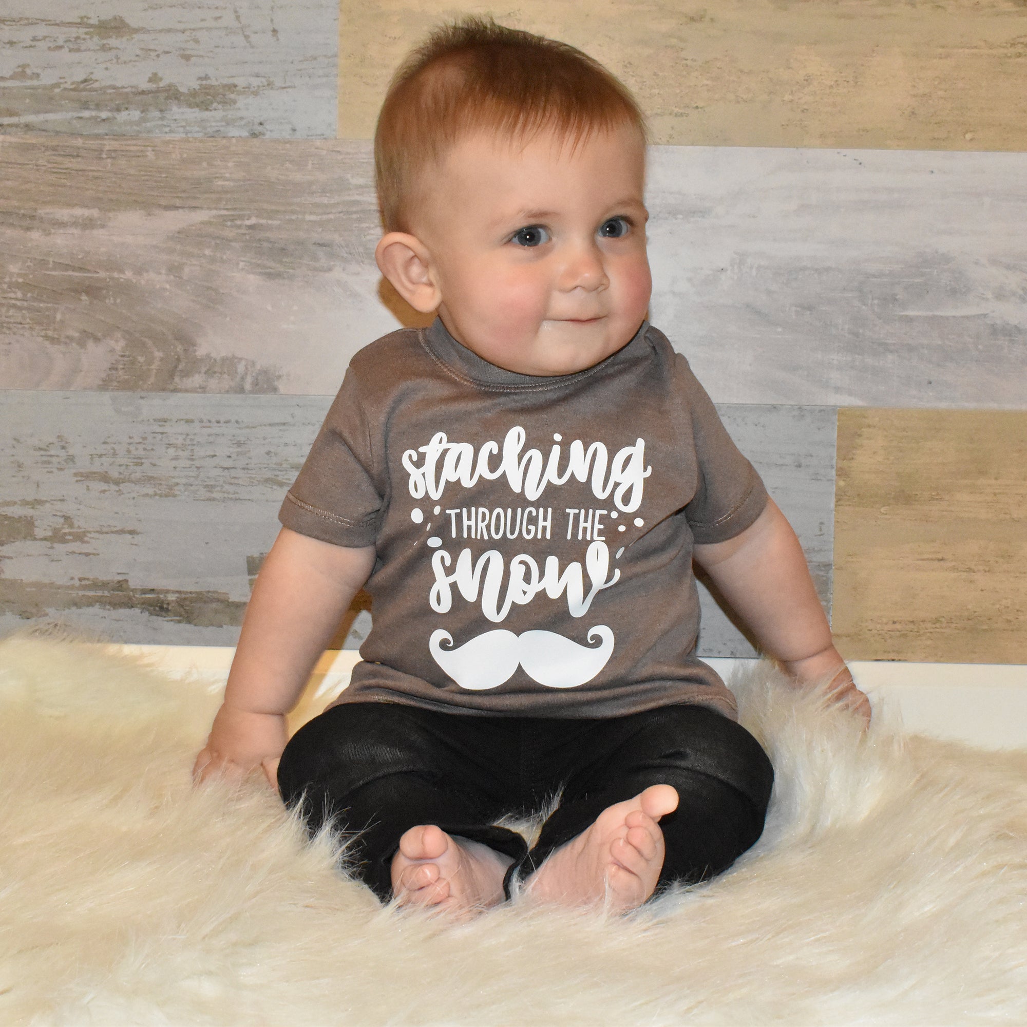 Toddler boy wearing mocha shirt, with 'Staching through the snow' print by KMLeon.