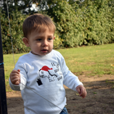 Little boy in park, wearing white shirt with long sleeves with dino 'Fla La La Rawr Rawr Rawr' print by KMLeon.