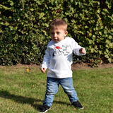 Little boy walking in the park, wearing white shirt with long sleeves with dino 'Fla La La Rawr Rawr Rawr' print by KMLeon.