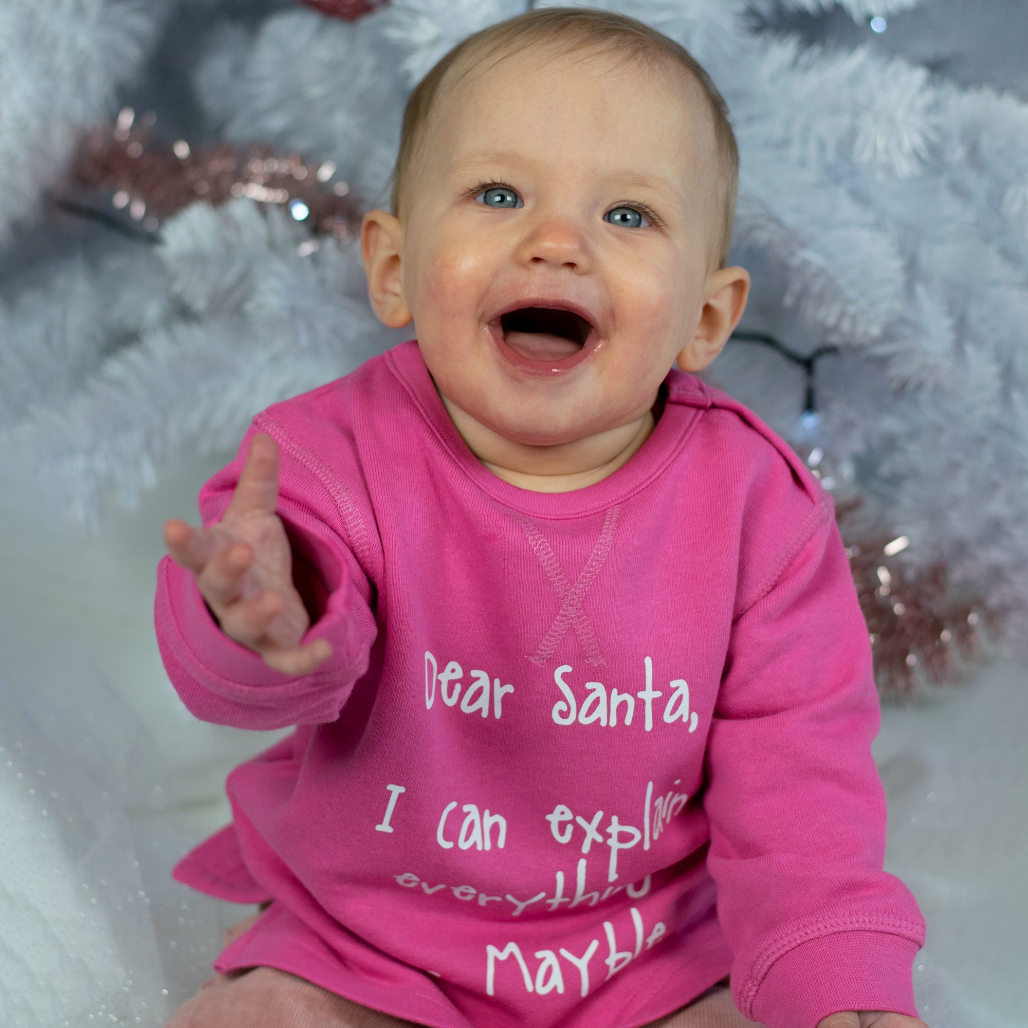 Baby girl with blue eyes and pink sweater with 'Santa, I can explain everything' sweater by KMLeon.