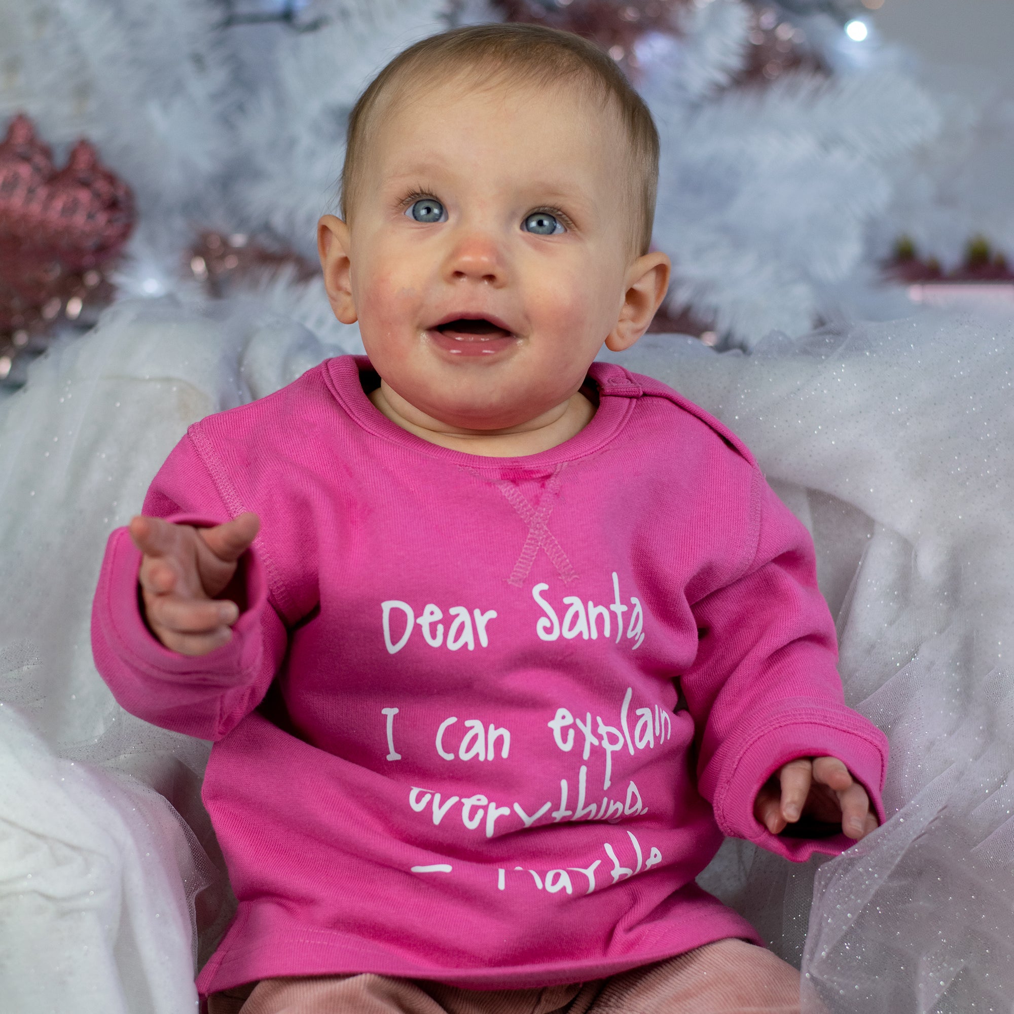 Baby girl with blue eyes and pink sweater with 'Santa, I can explain everything' sweater by KMLeon.