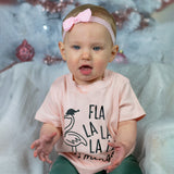 Baby girl with blue eyes, wearing a ppink headband and pink shirt, with 'Fla la la la la mingo' print by KMLeon.