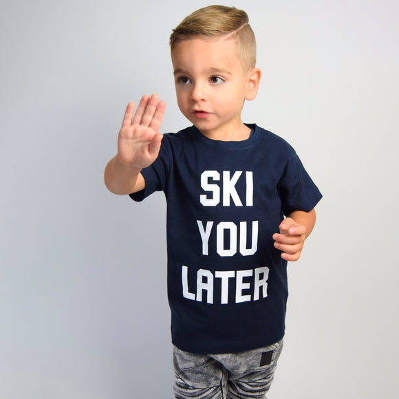 Boy wearing navy shirt with 'Ski je later' print by KMLeon, with hand in stop position.