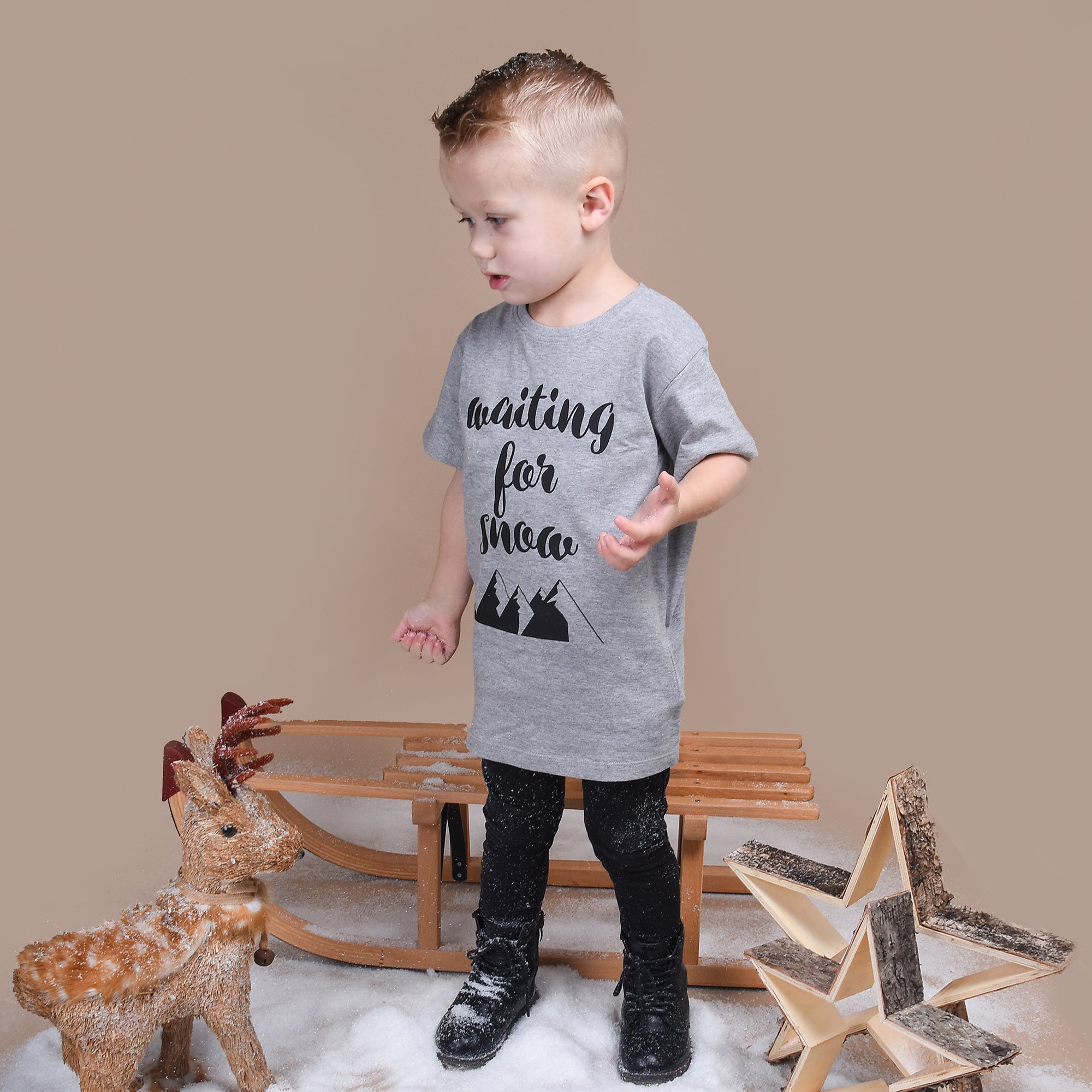 Blonde boy, wearing heather grey shirt with 'Waiting for snow' print by KMLeon.