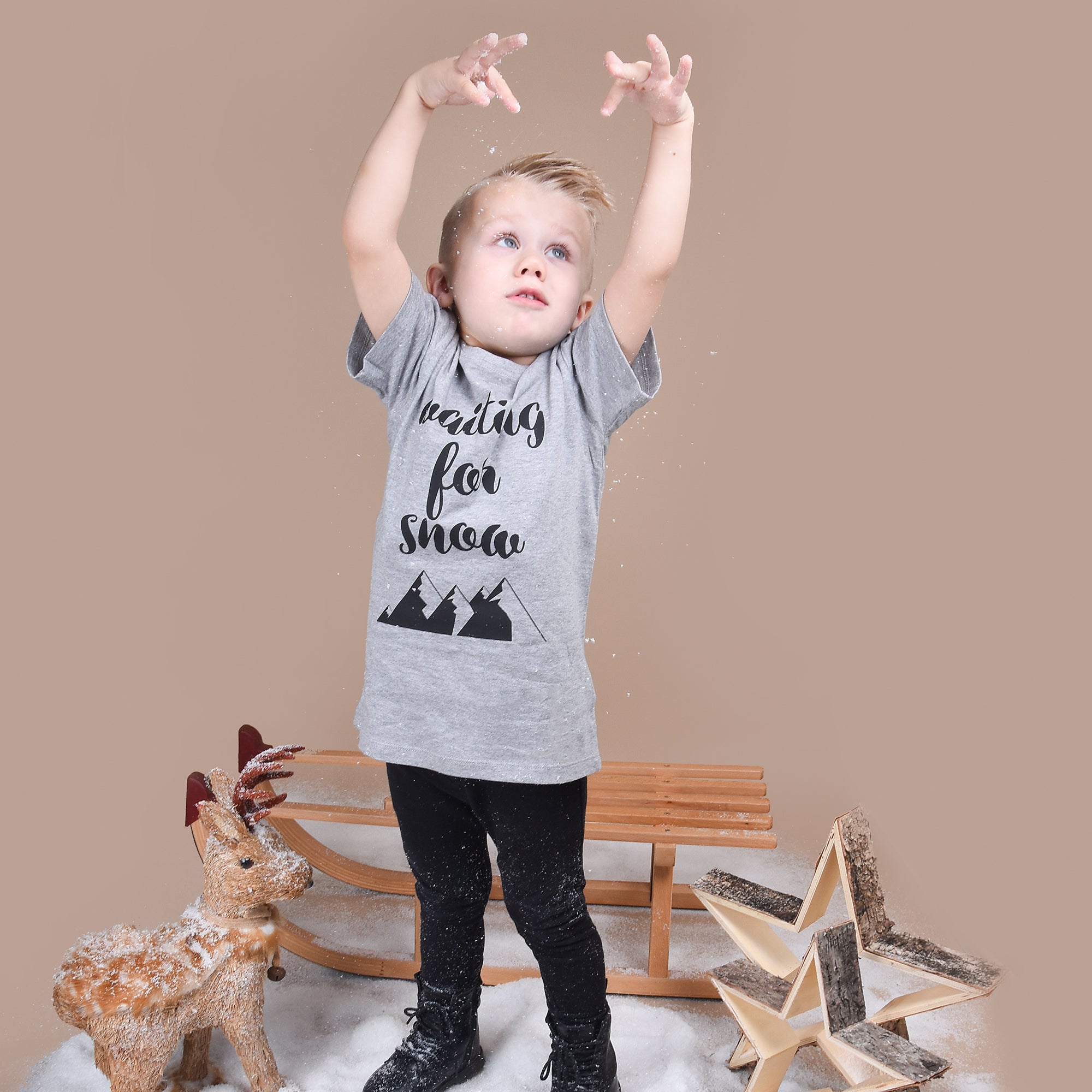 Blonde boy throwing with snow, wearing heather grey shirt with 'Waiting for snow' print by KMLeon.