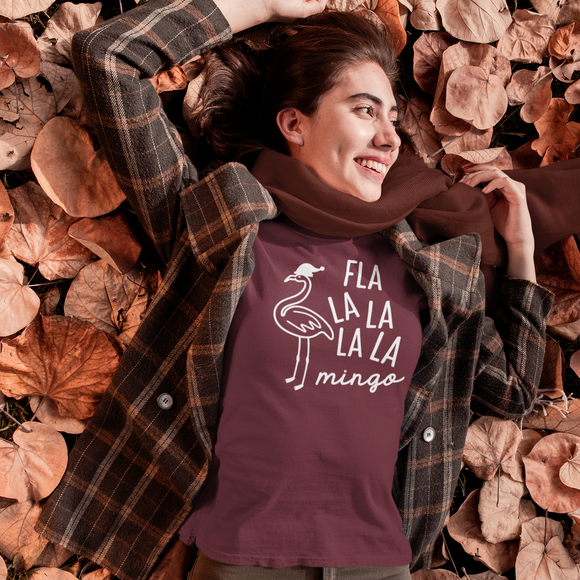 Smiling woman with burgundy shirt with 'Fla la la la la mingo' print by KMLeon, laying on autumn leaves.