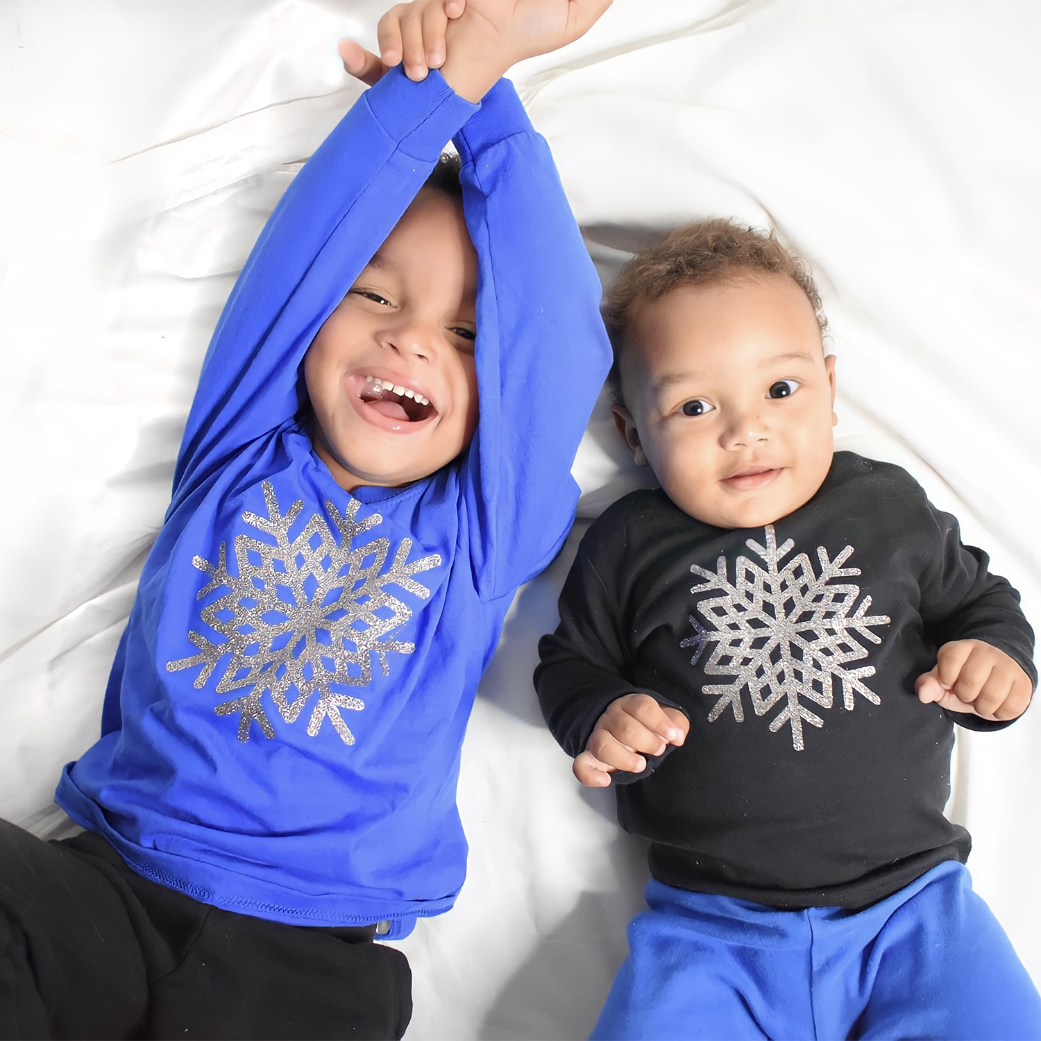Happy young black brothers wearing shirts with long sleeves with glitter snow star print by KMLeon.