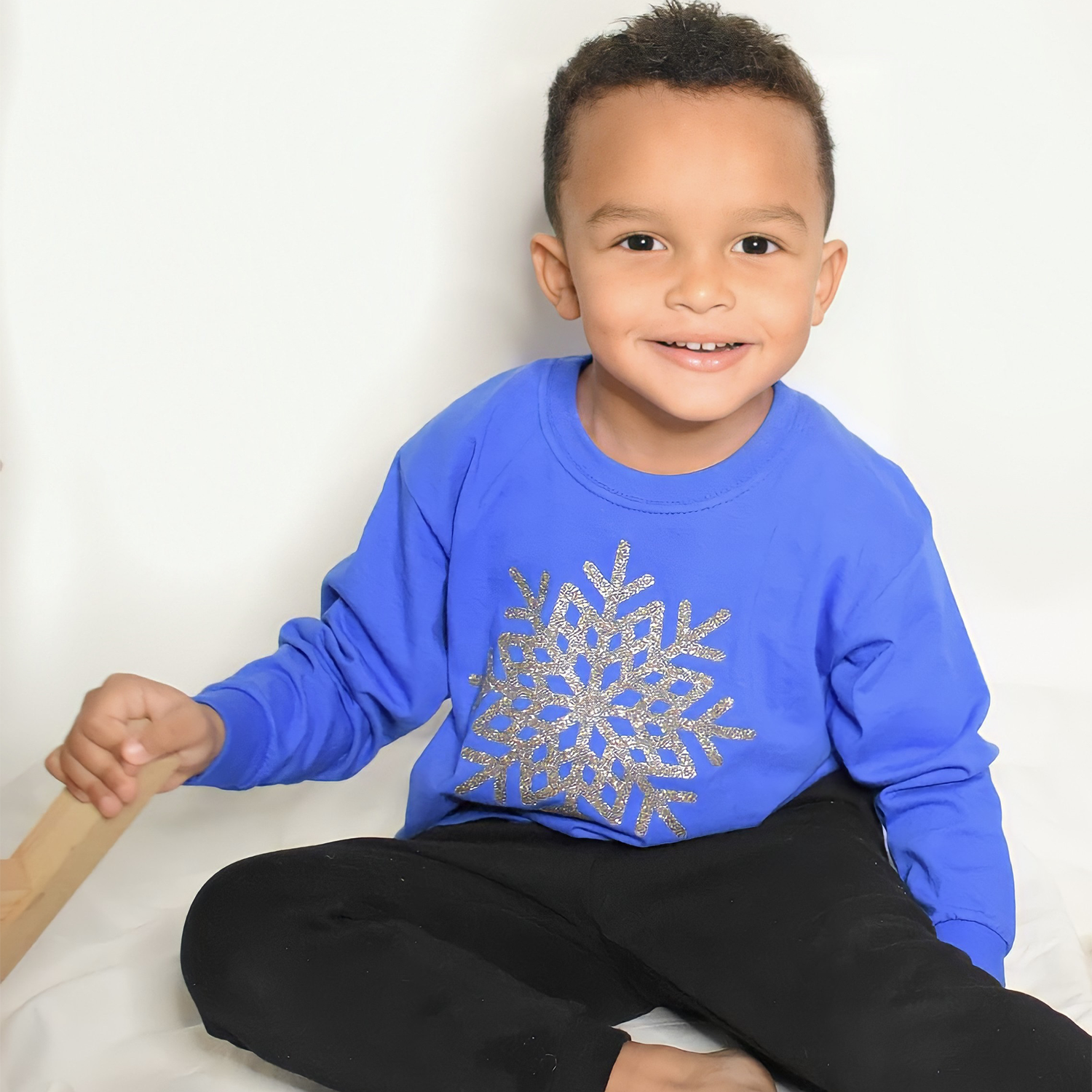 Smiling black boy wearing blue shirt with glitter snow star print by KMLeon.