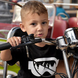 Young boy wearing black shirt with ski goggles print by KMLeon on motorcycle. 