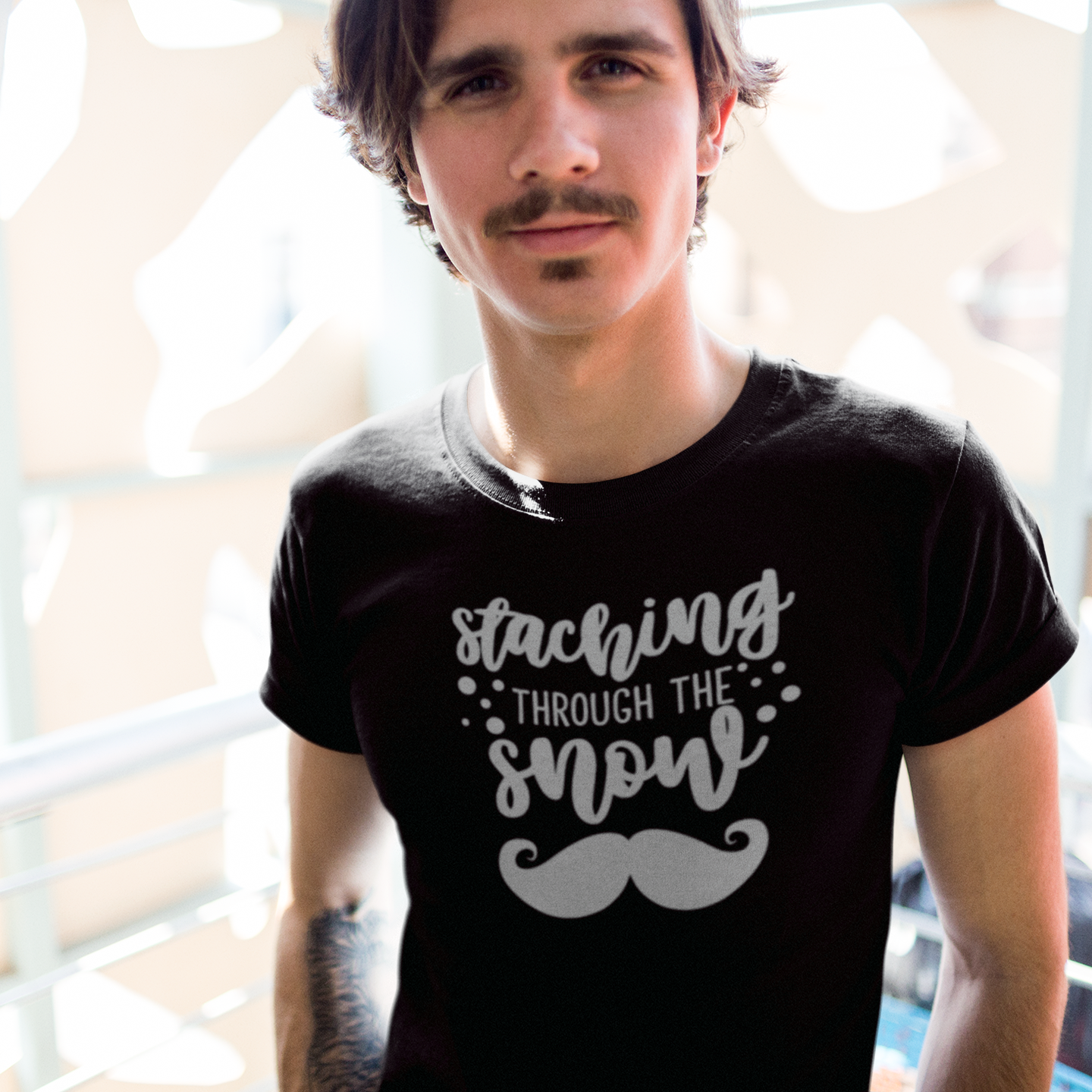 Man with mustache wearing black shirt with 'Staching through the snow' print by KMLeon.