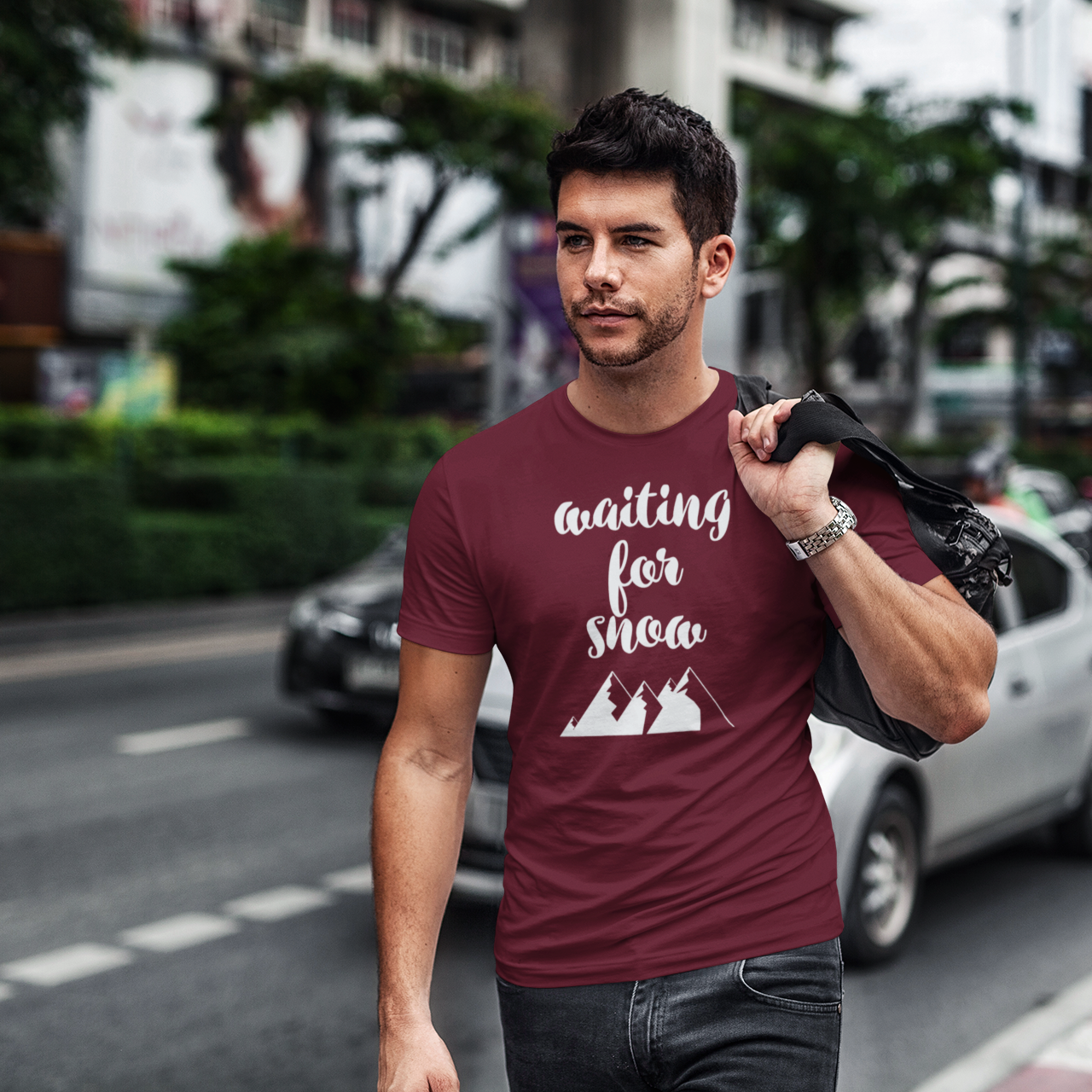Man walking in city holding bag wearing burgundy shirt with 'Waiting for snow' print by KMLeon.